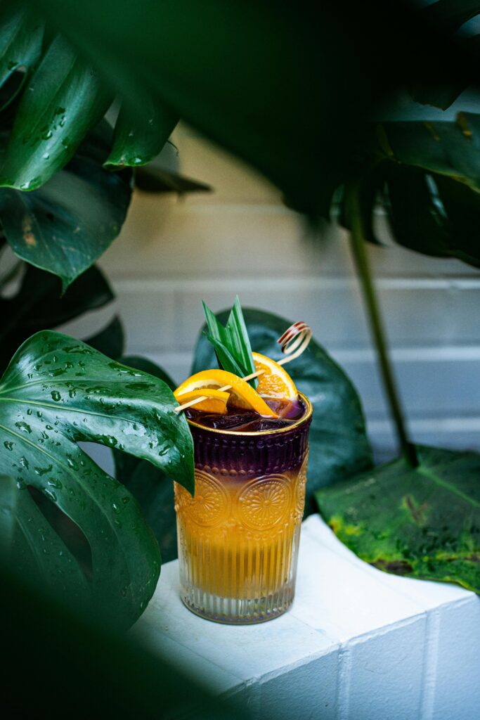 Vibrant cocktail with lemon slices amidst lush tropical plants in Ho Chi Minh City.